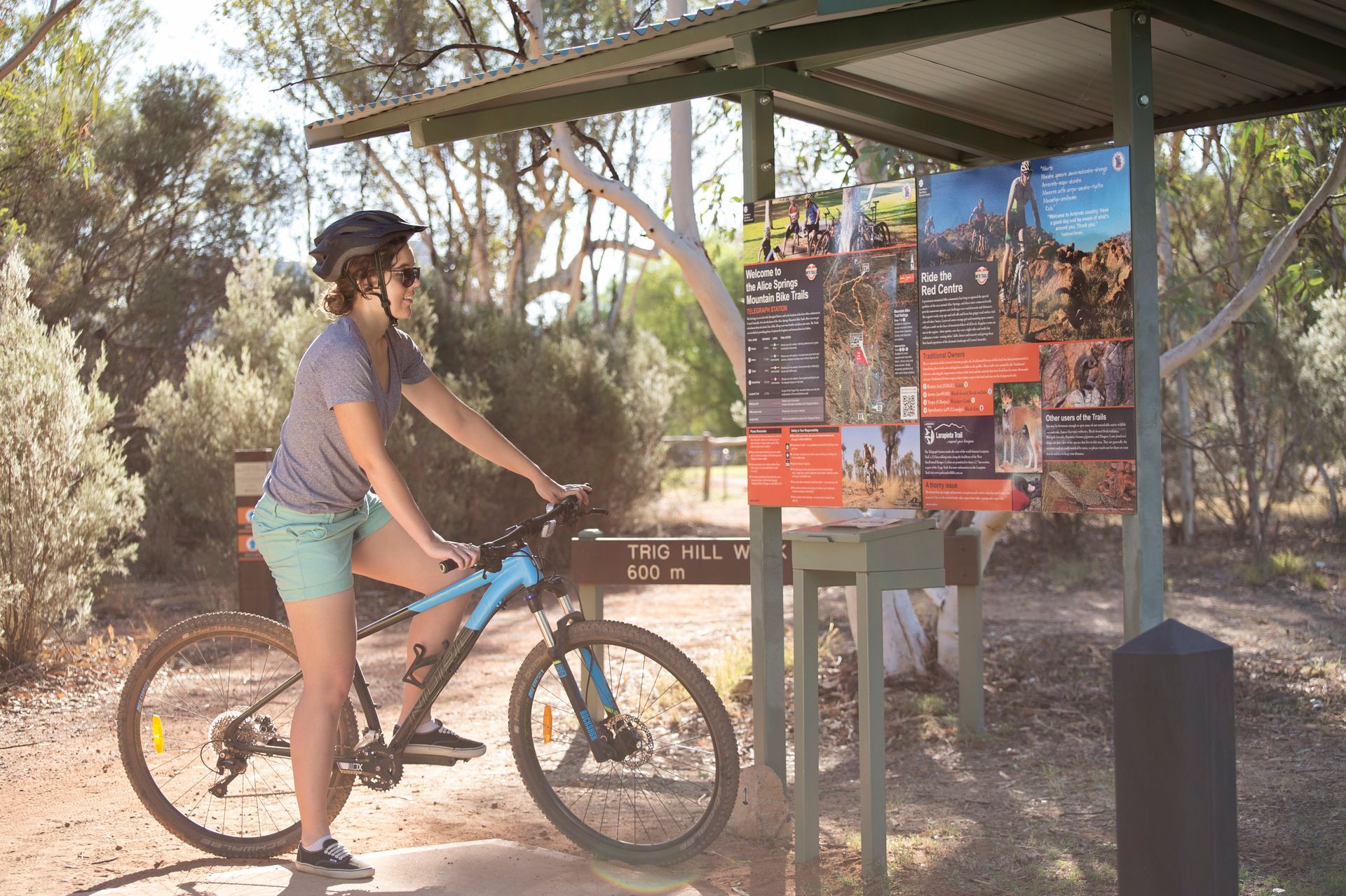 A woman is riding a bike next to a sign.
