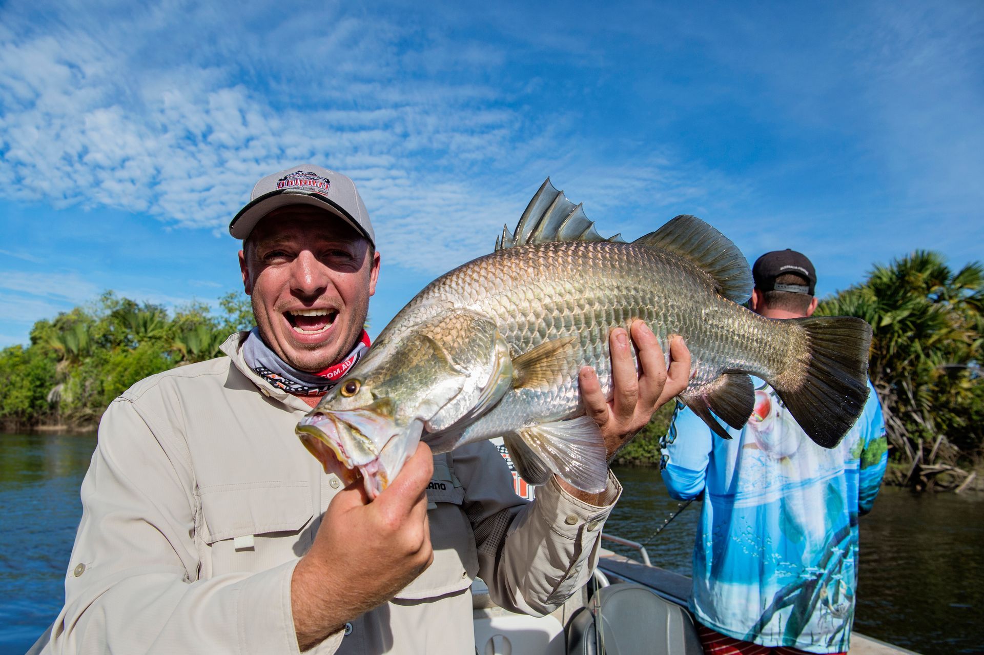 A man is holding a large fish in his hands on a boat.