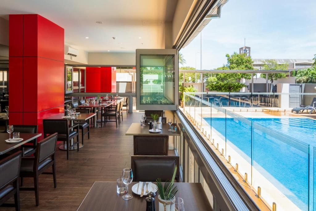 A restaurant with tables and chairs and a view of a swimming pool.