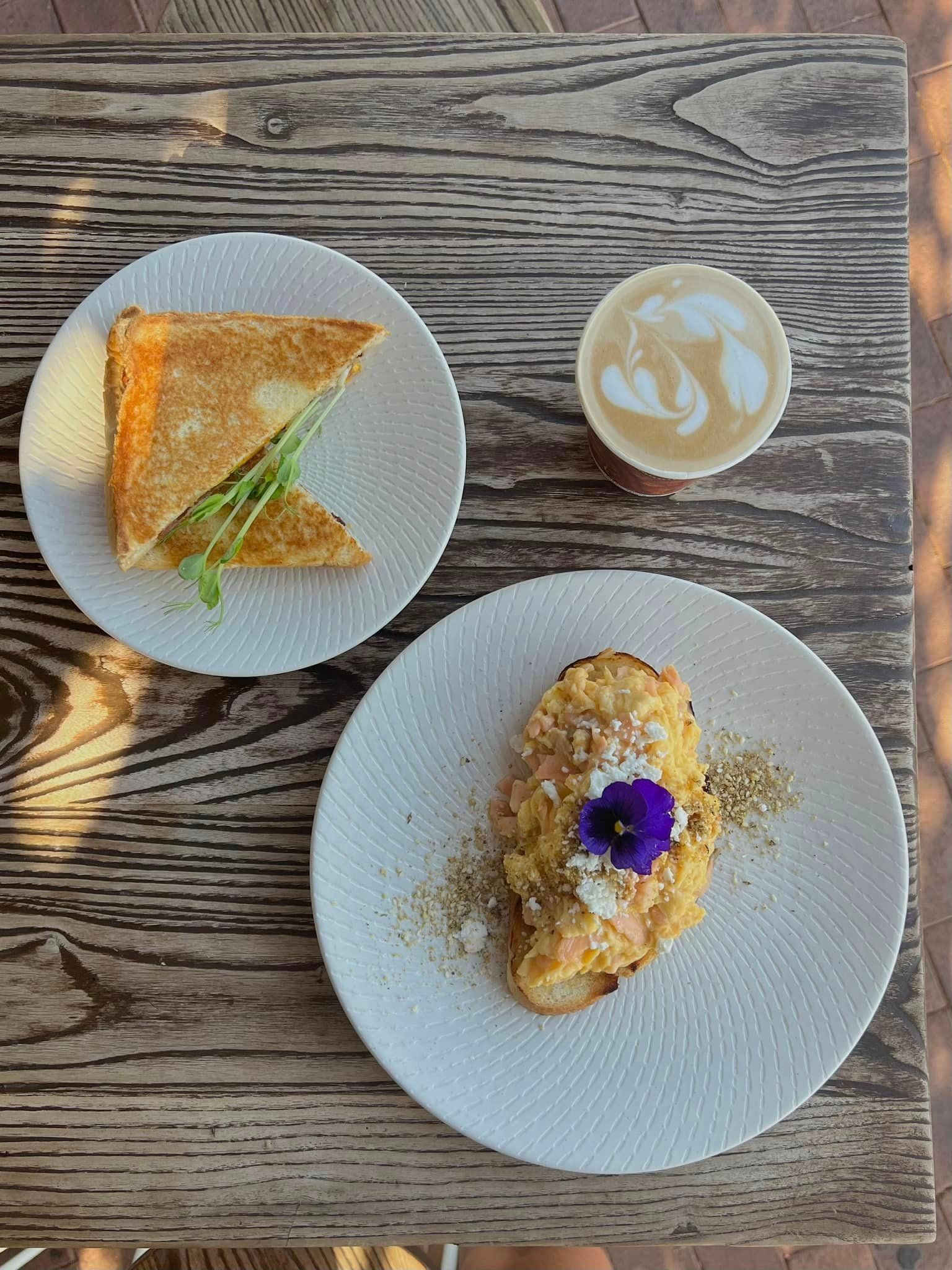 A wooden table topped with plates of food and a cup of coffee.
