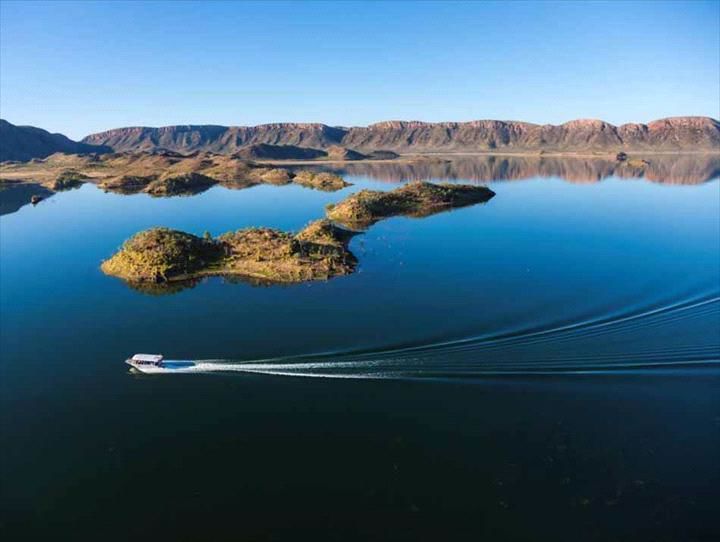 A boat is floating on a lake with mountains in the background.