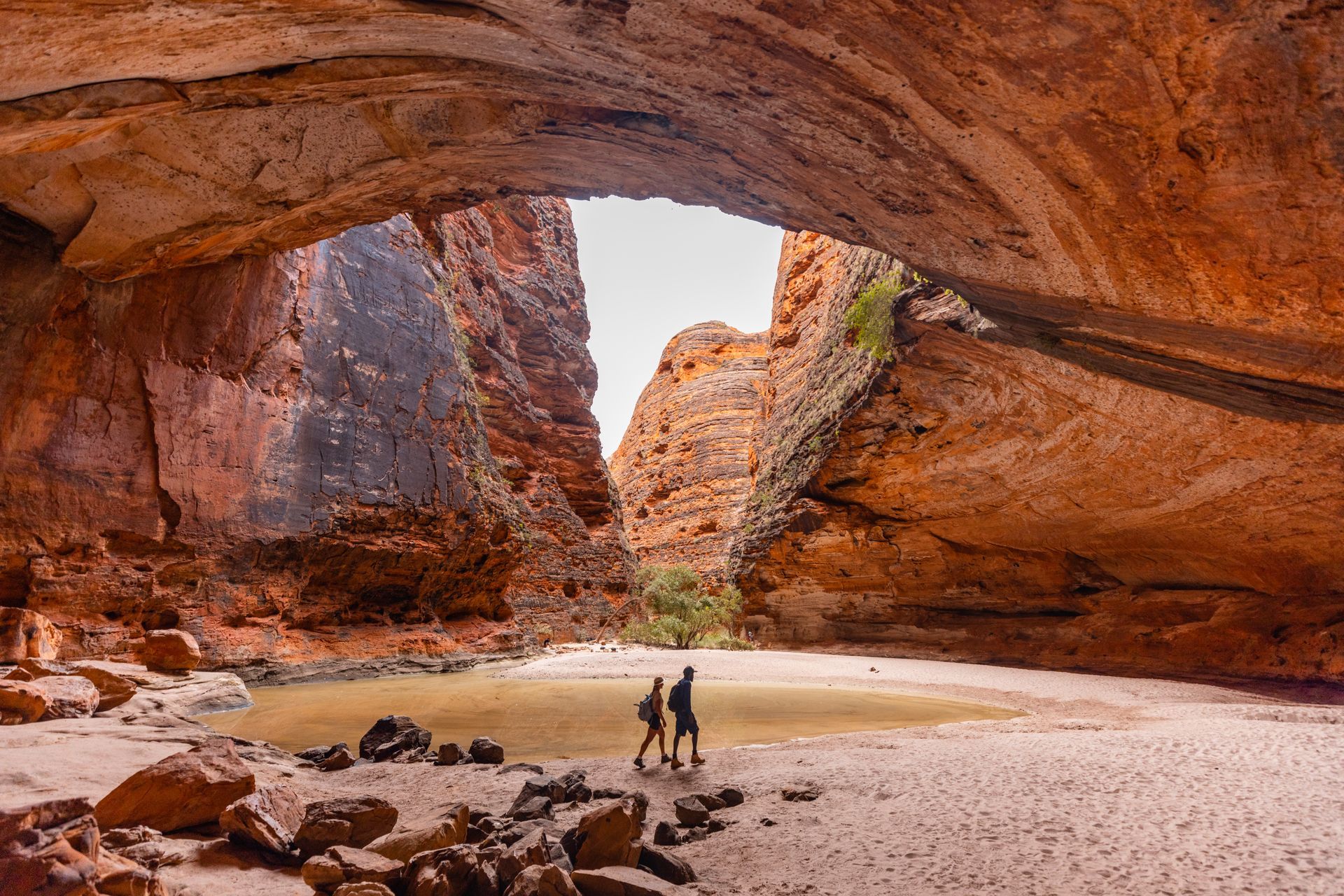 A couple is walking through a cave in the desert.