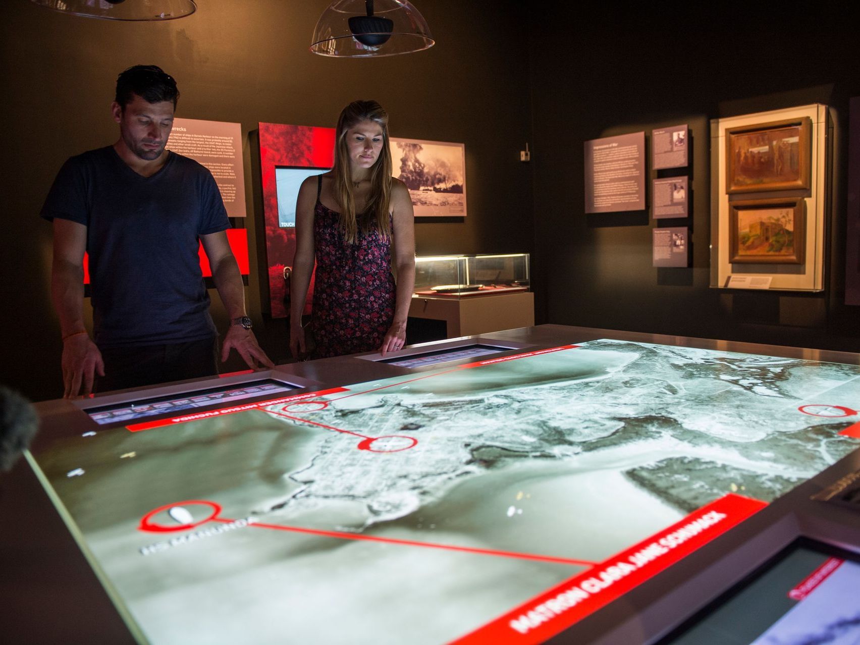 A man and a woman are looking at a large screen in a museum.