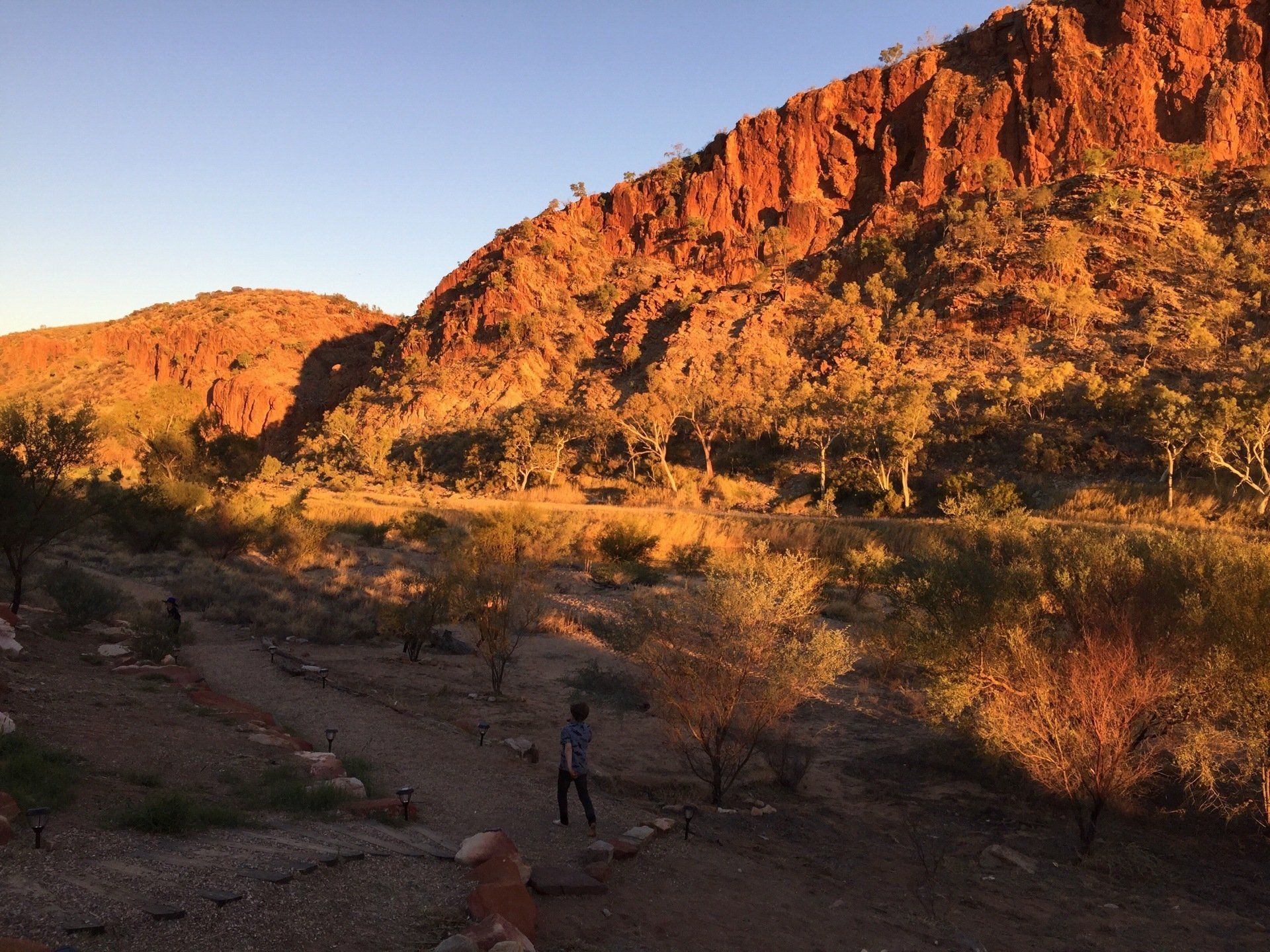 A person is walking in the desert near a mountain