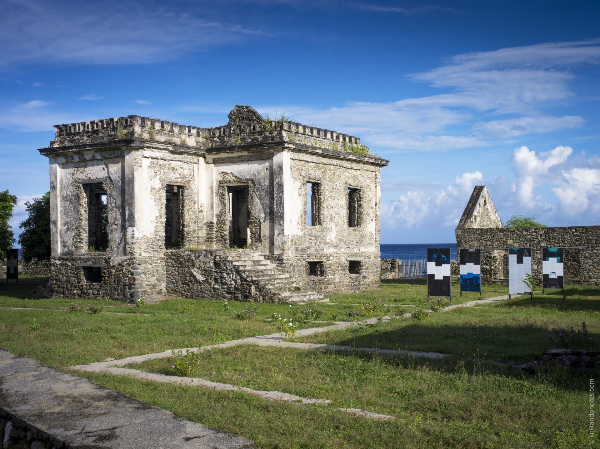 A large stone building is sitting in the middle of a grassy field.