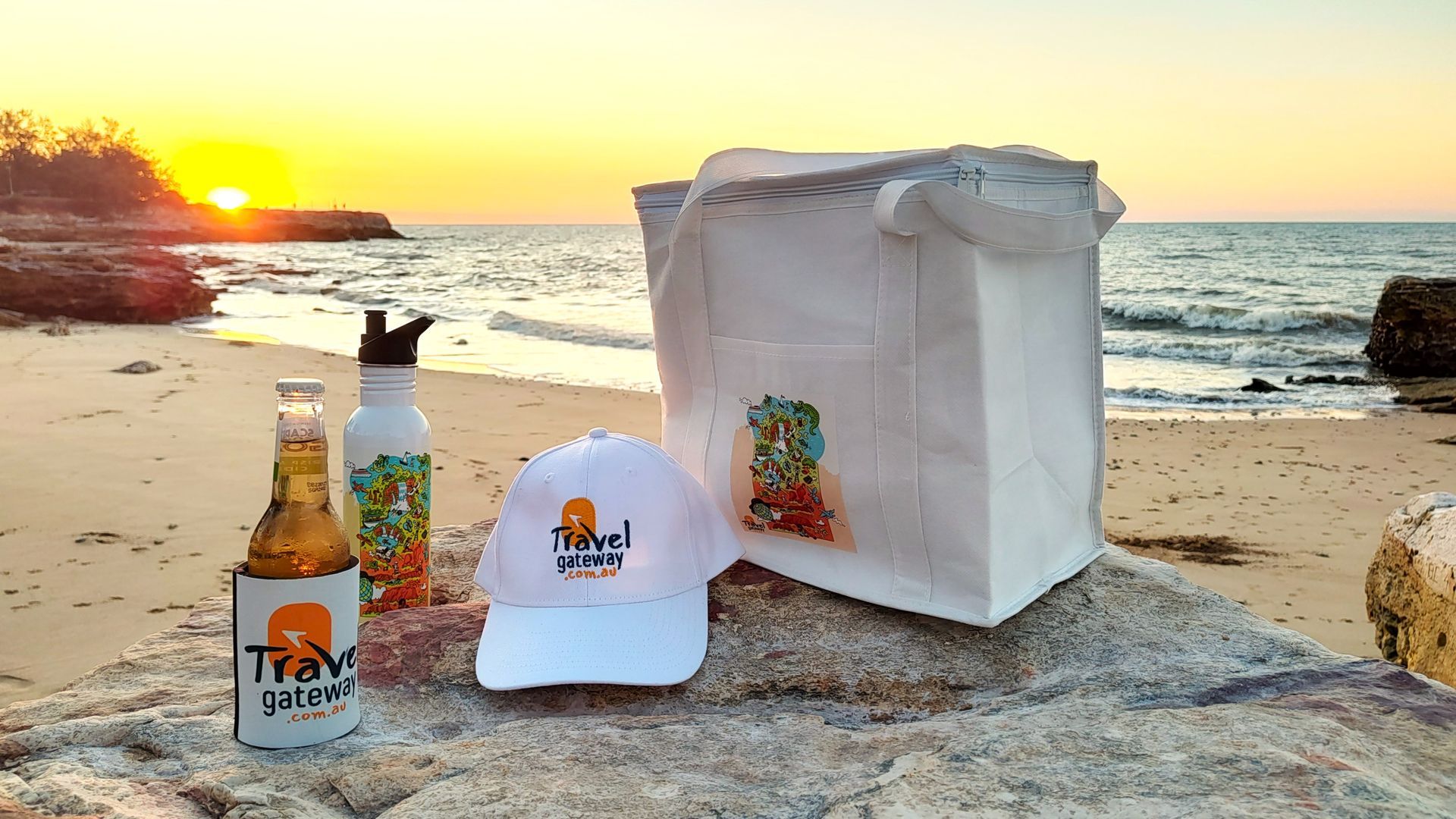 A bottle of beer a hat and a bag are on the beach