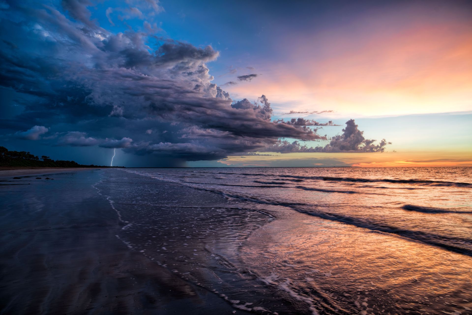 A storm is coming in over the ocean at sunset.