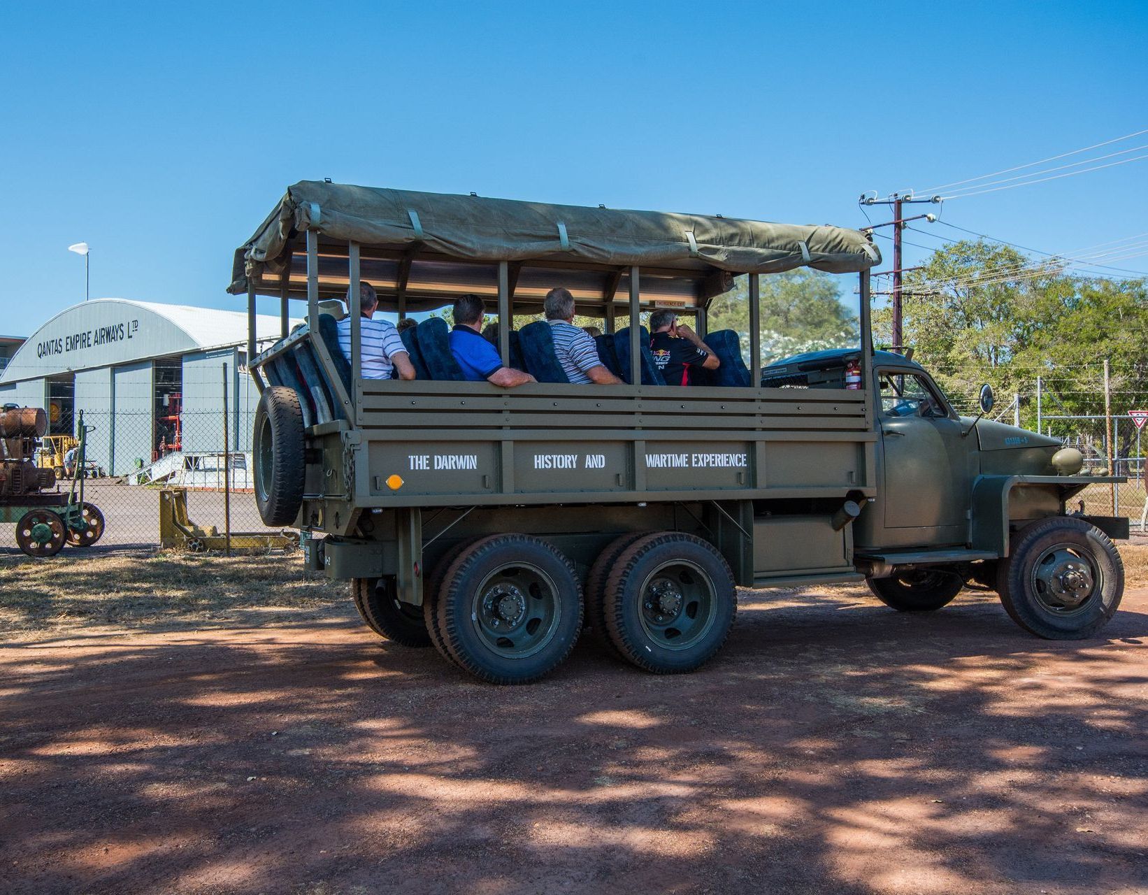 A group of people are riding on the back of a military truck.