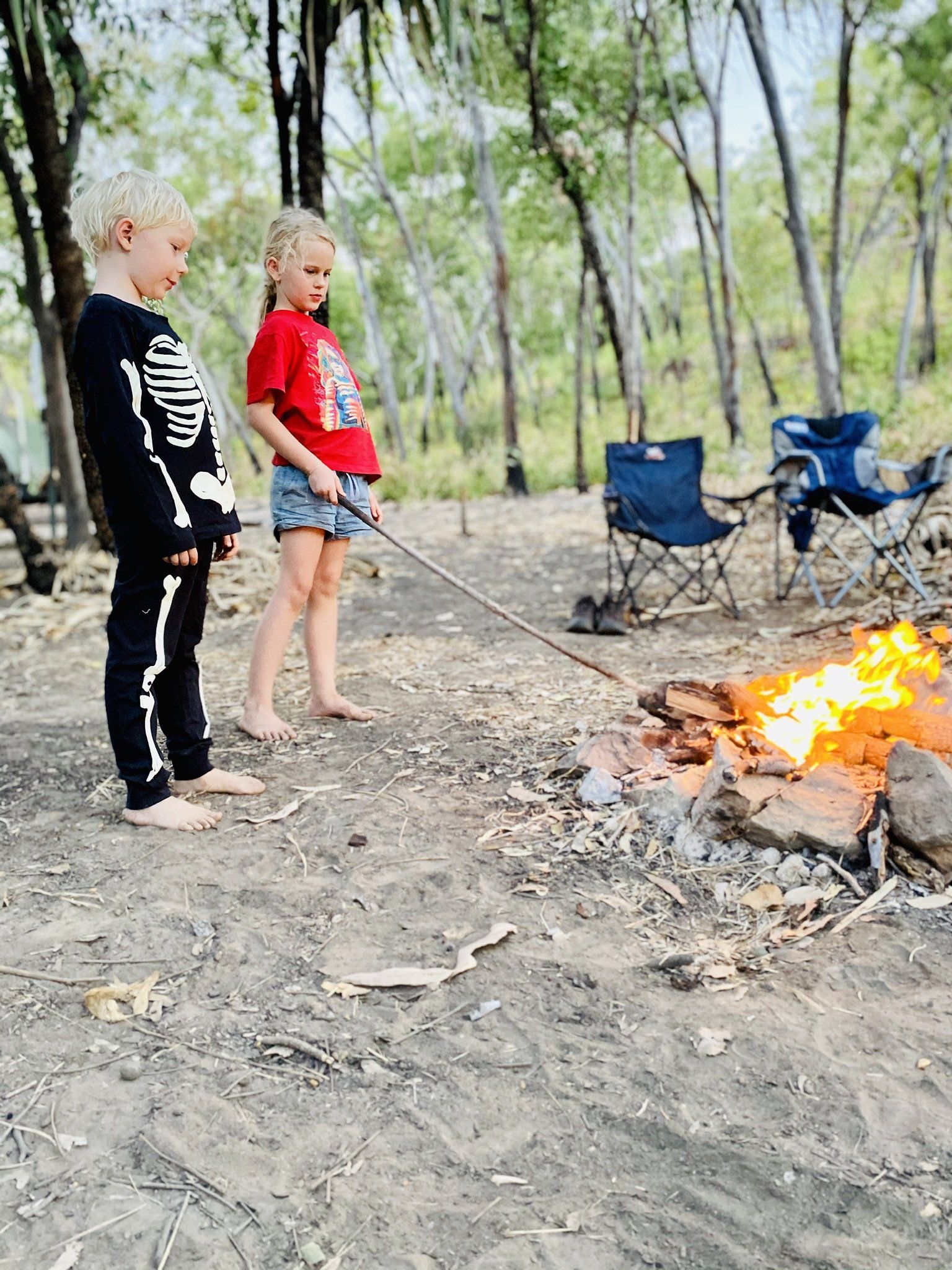 A boy and a girl are roasting marshmallows over a campfire.