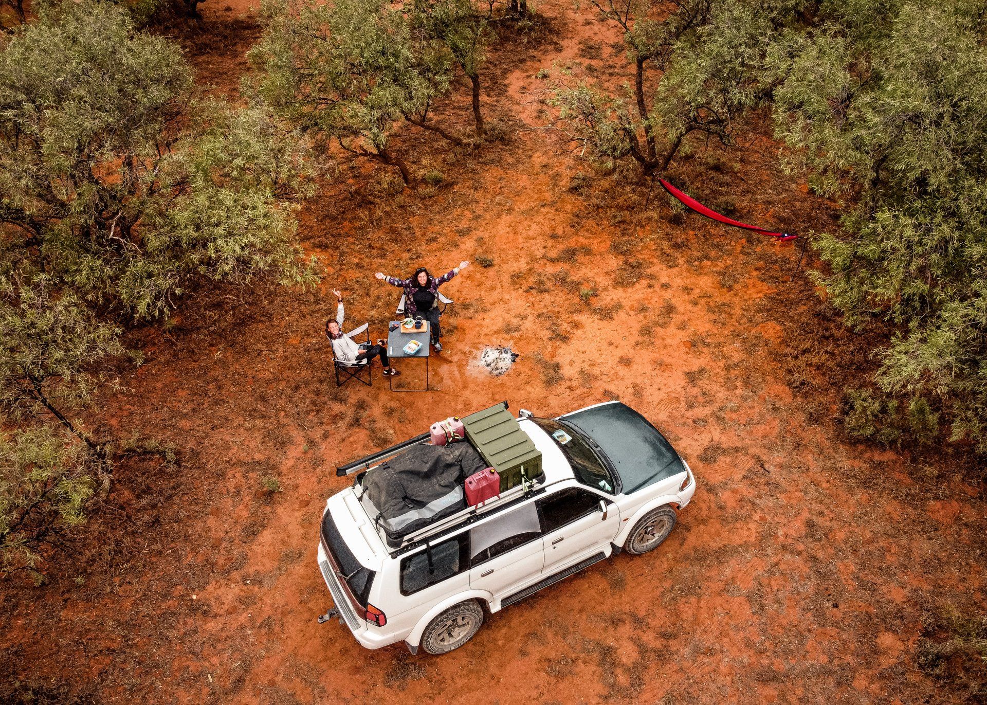 An aerial view of a car parked in the middle of a forest.
