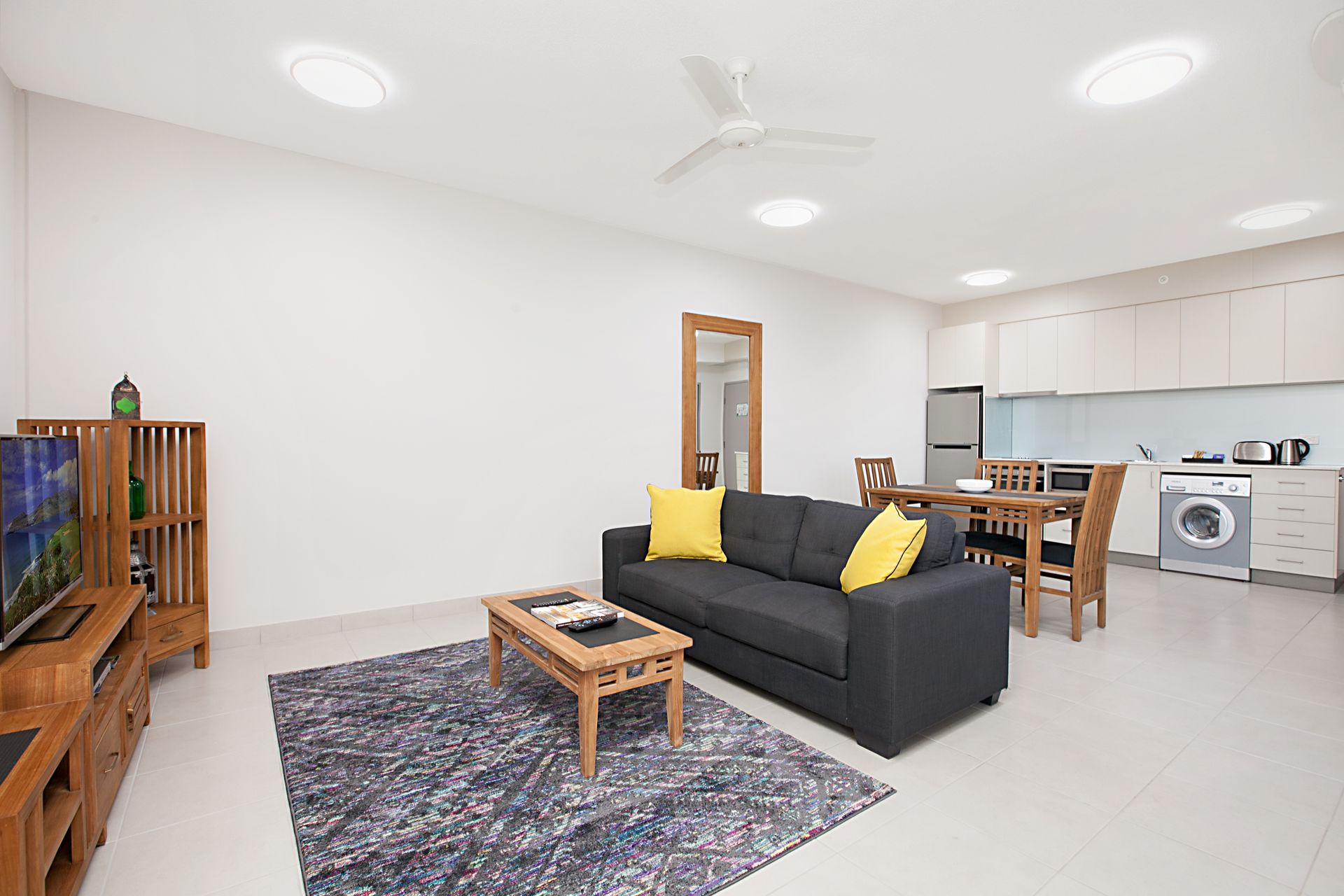 A living room with a couch , table , chairs and a flat screen tv.