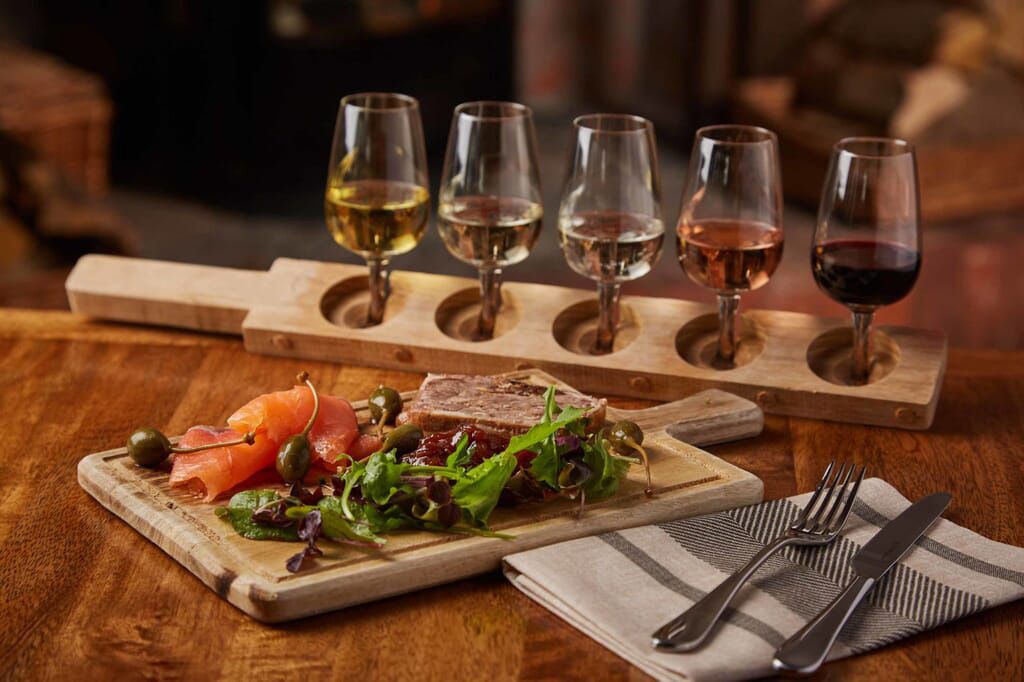 a wooden cutting board with food and wine glasses on it