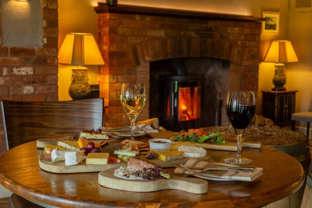a table with food and wine in front of a fireplace