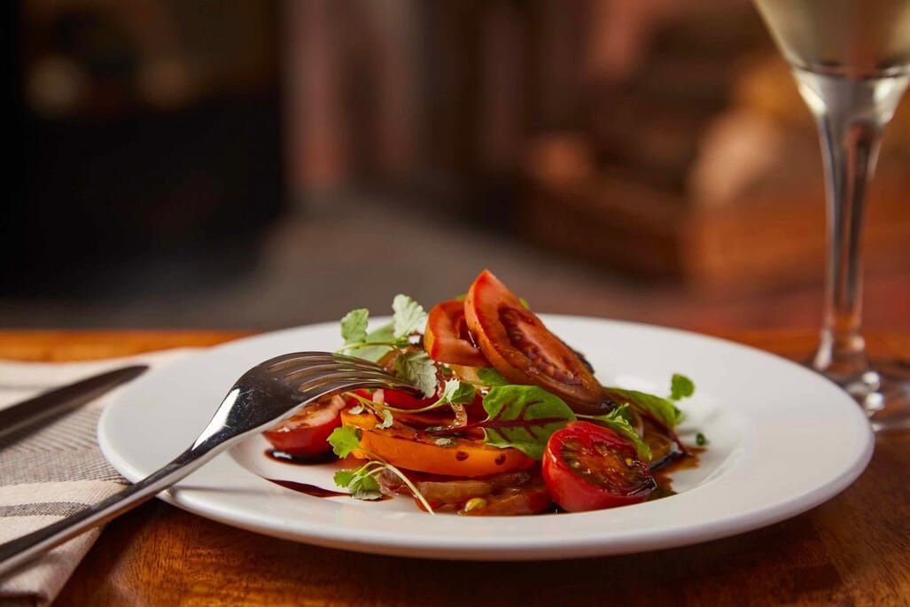 a plate of food with tomatoes and a glass of wine