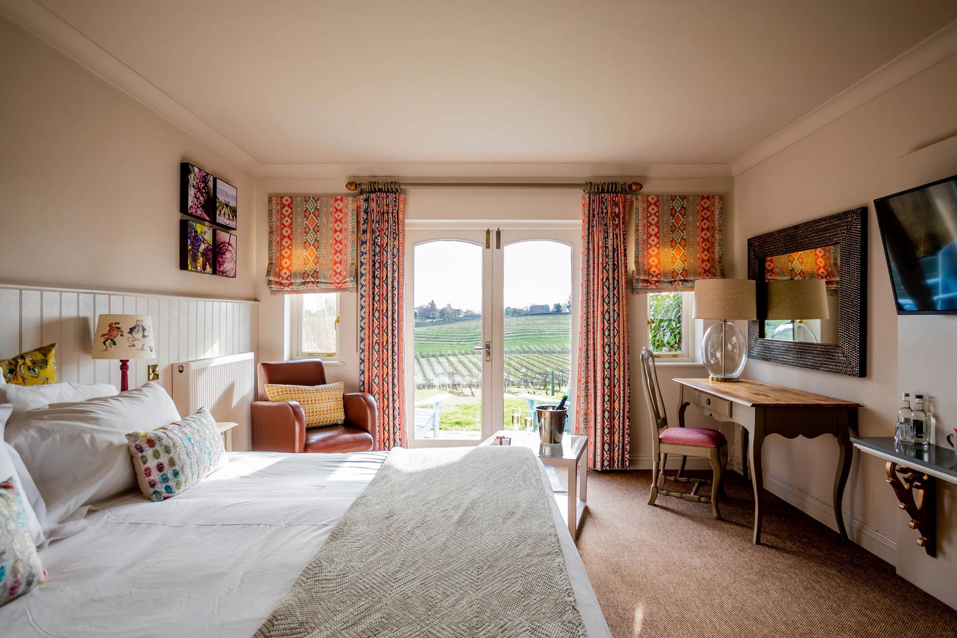 A Vineyard View room with a large bed , desk , chair and television.
