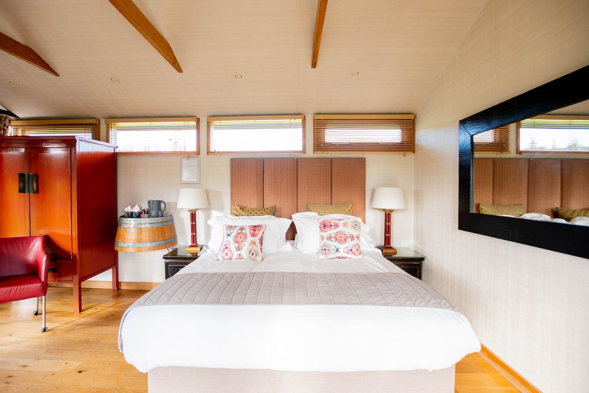 Bedroom with a large bed, two nightstands, a red wardrobe, and a large mirror on the wall.