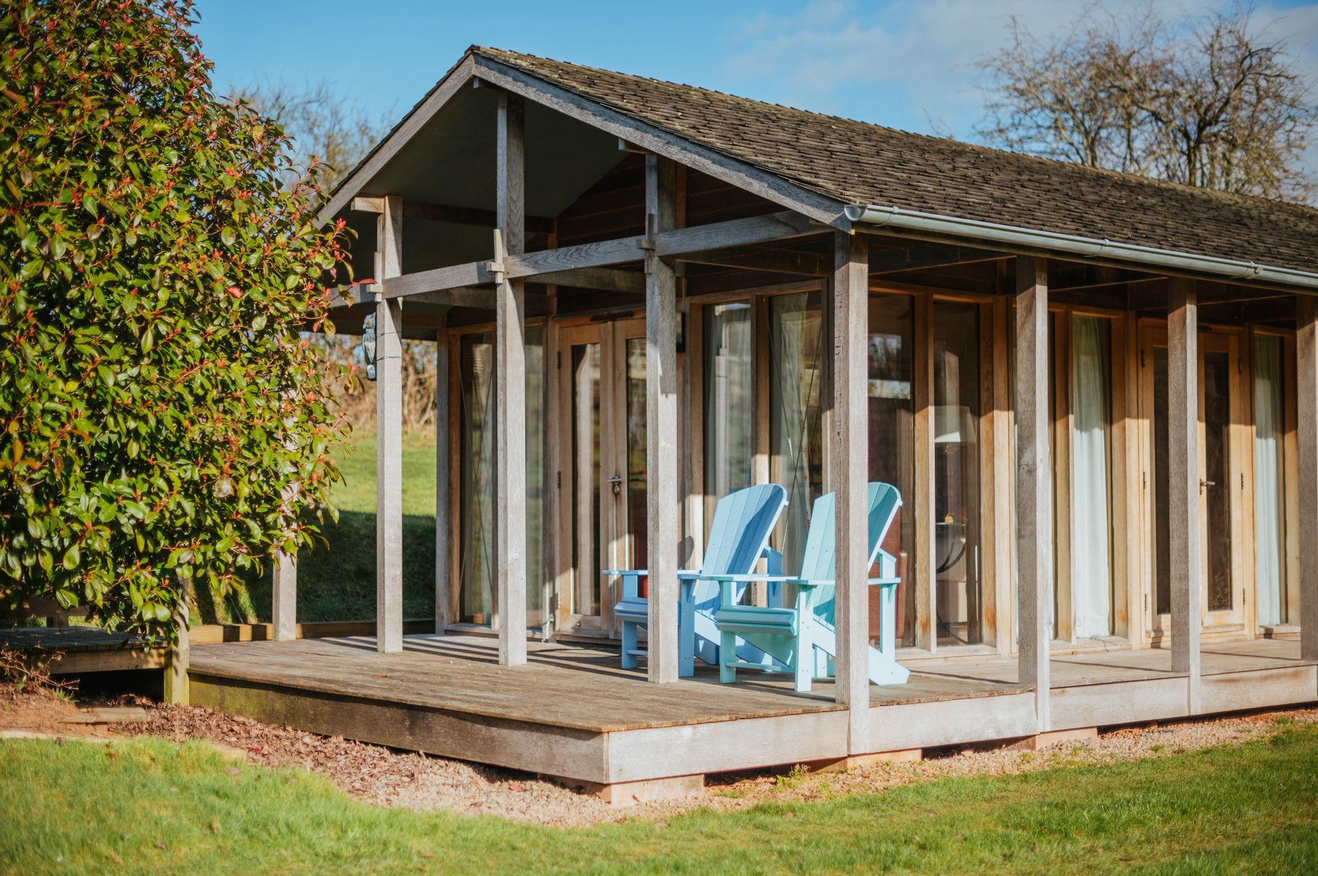a small house with blue chairs on the porch