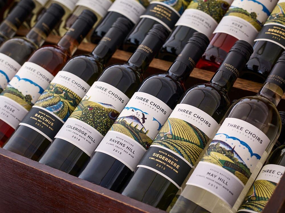 A selection of wine bottles in a cabinet which have been produced by Three Choirs Vineyard