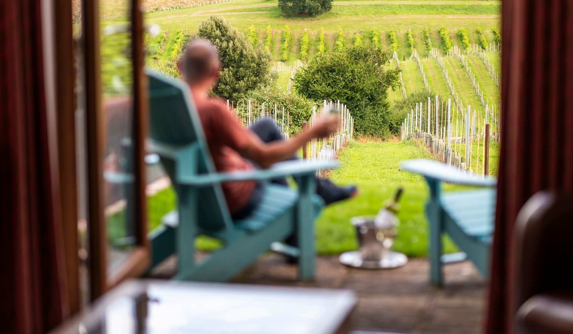 A man is sitting in a patio chair with a glass of wine.