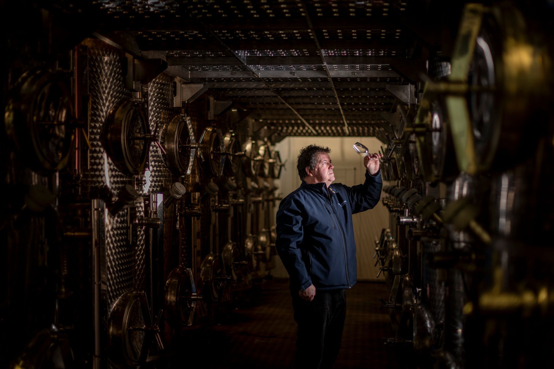 a man in a blue jacket is standing in a dark room