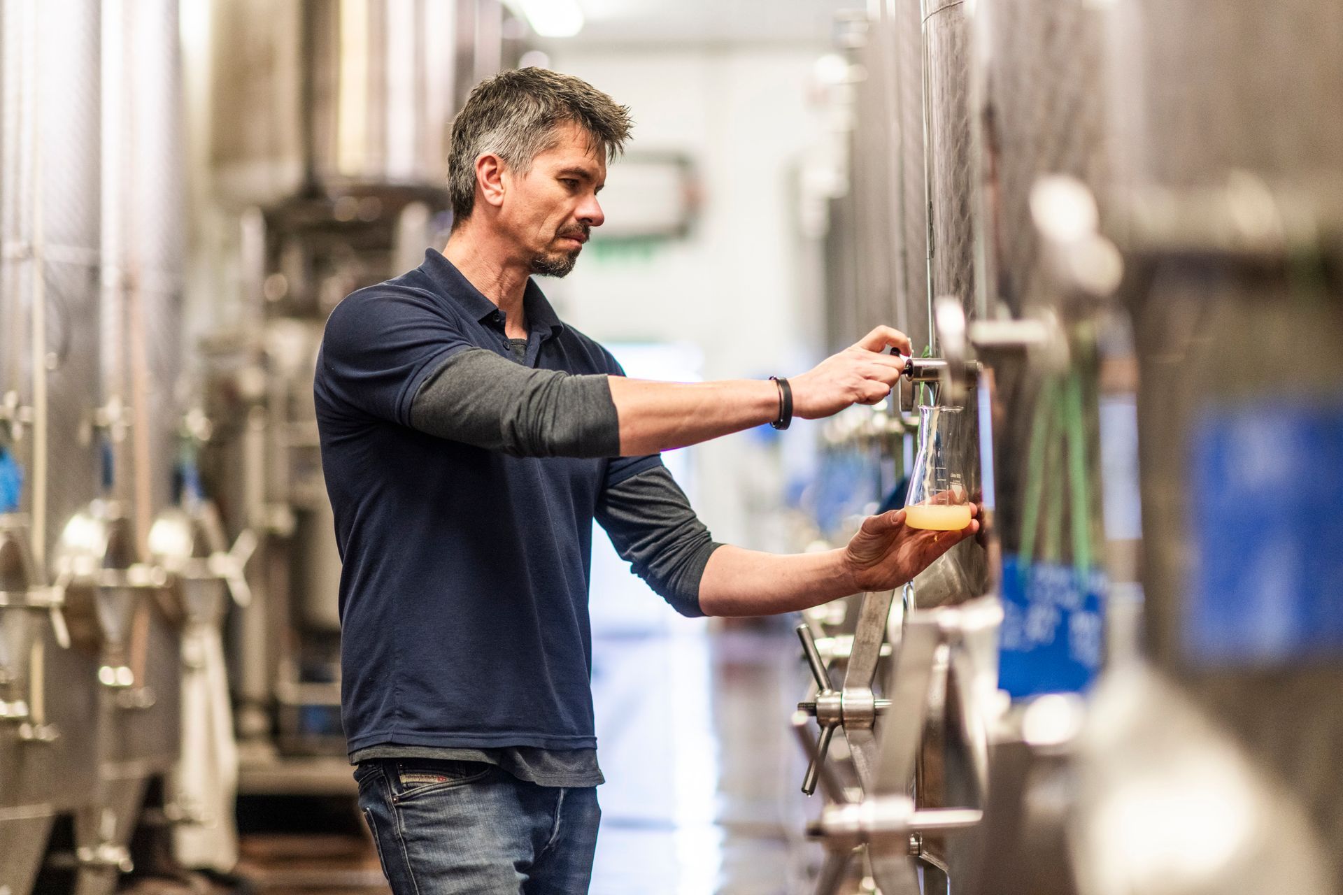 a man is pouring liquid into a glass in a factory .