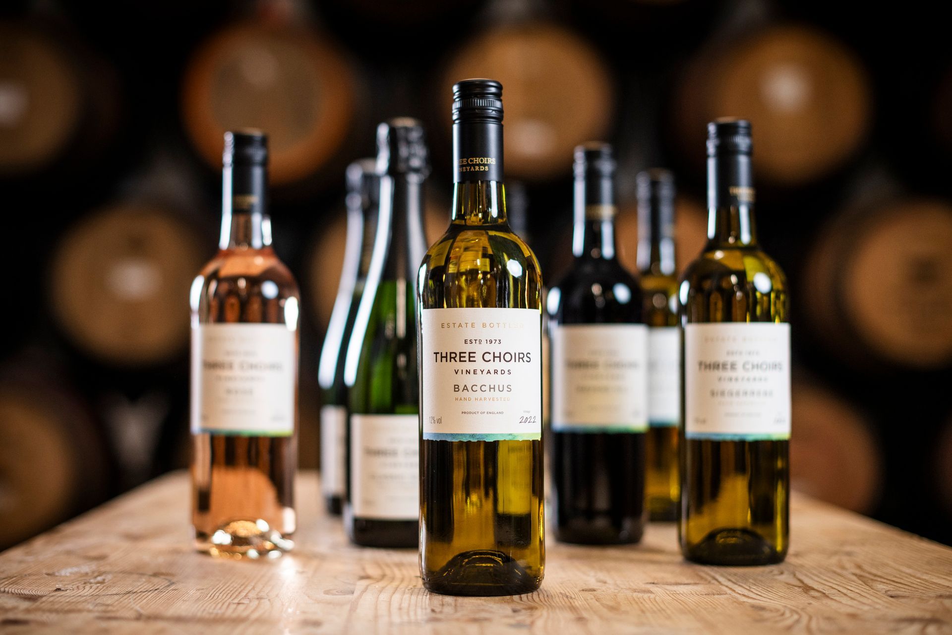 Several bottles of wine are lined up on a wooden table, labelled Three Choirs Vineyards