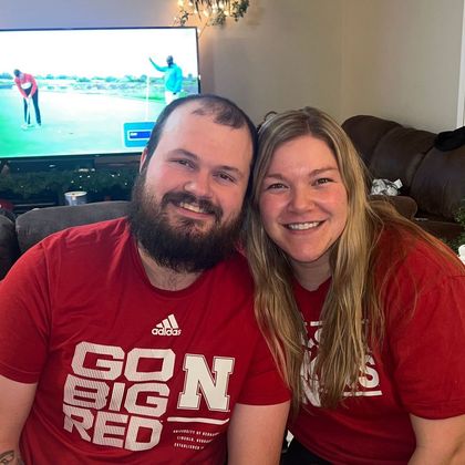 A man and a woman are posing for a picture in front of a television