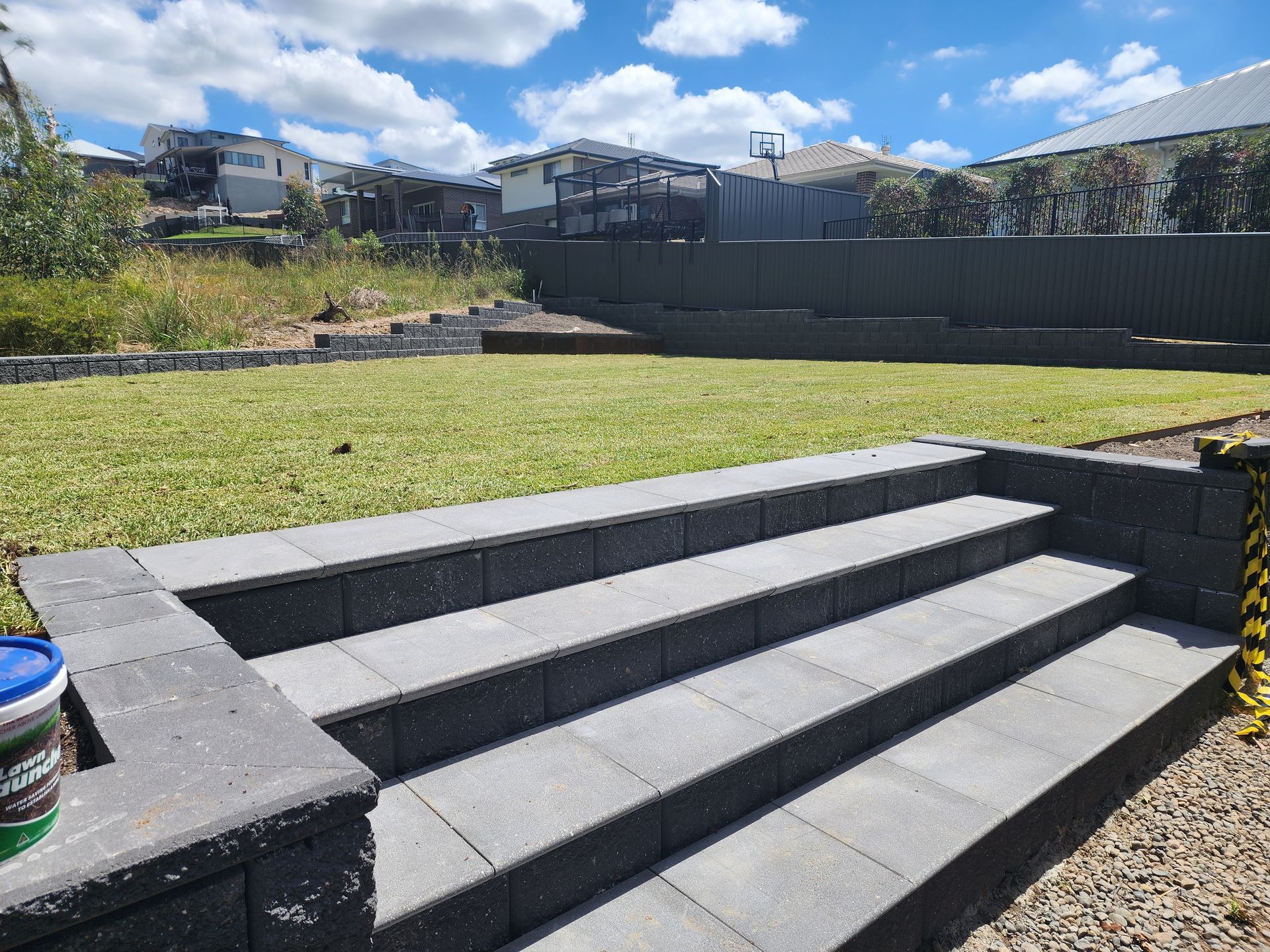 A Hose Is Sitting In The Grass Next To A Fence — Green Envy Landscape & Garden Services In Cameron Park NSW