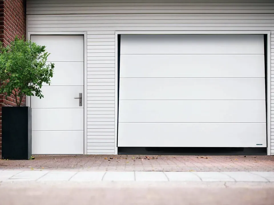 A white garage door is open and a white door is closed.
