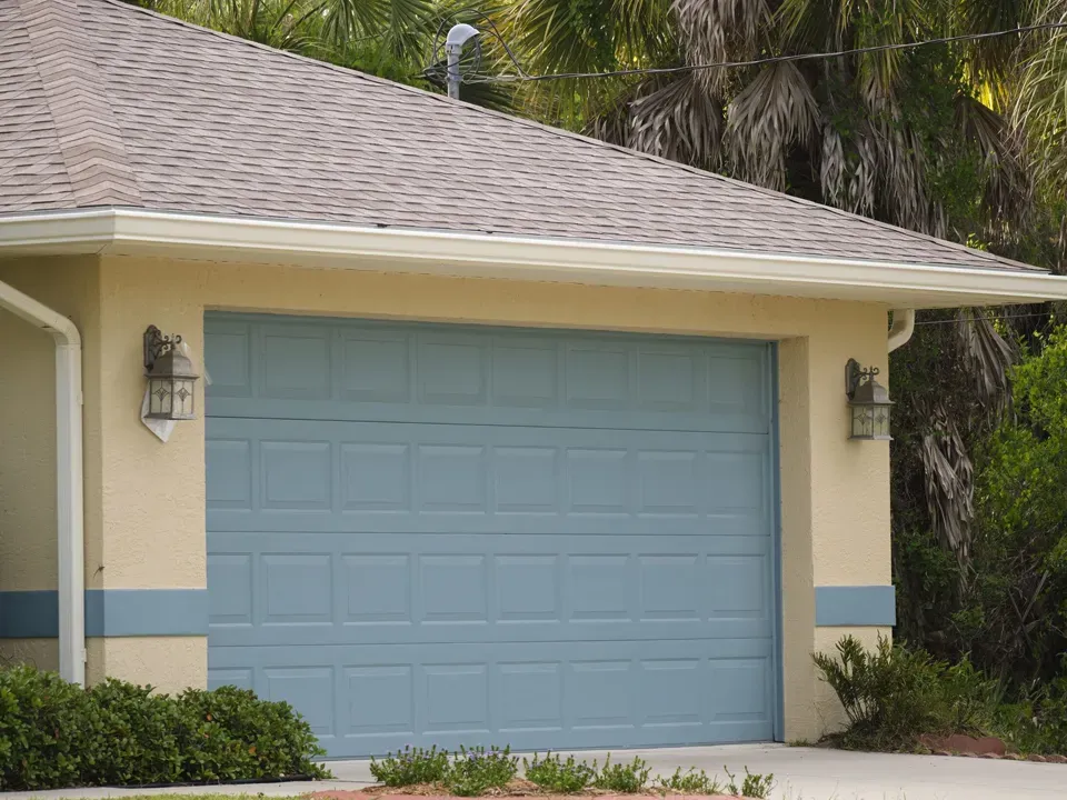 A house with a blue garage door and a roof