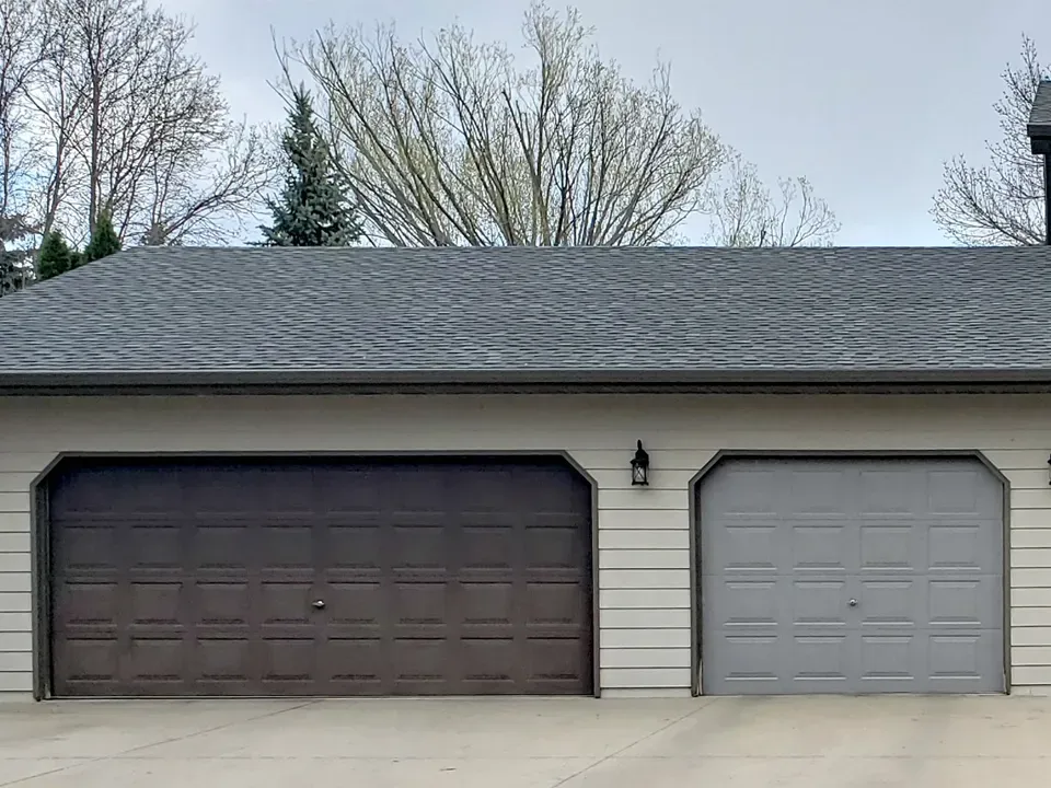 A garage with two garage doors and a gray roof.