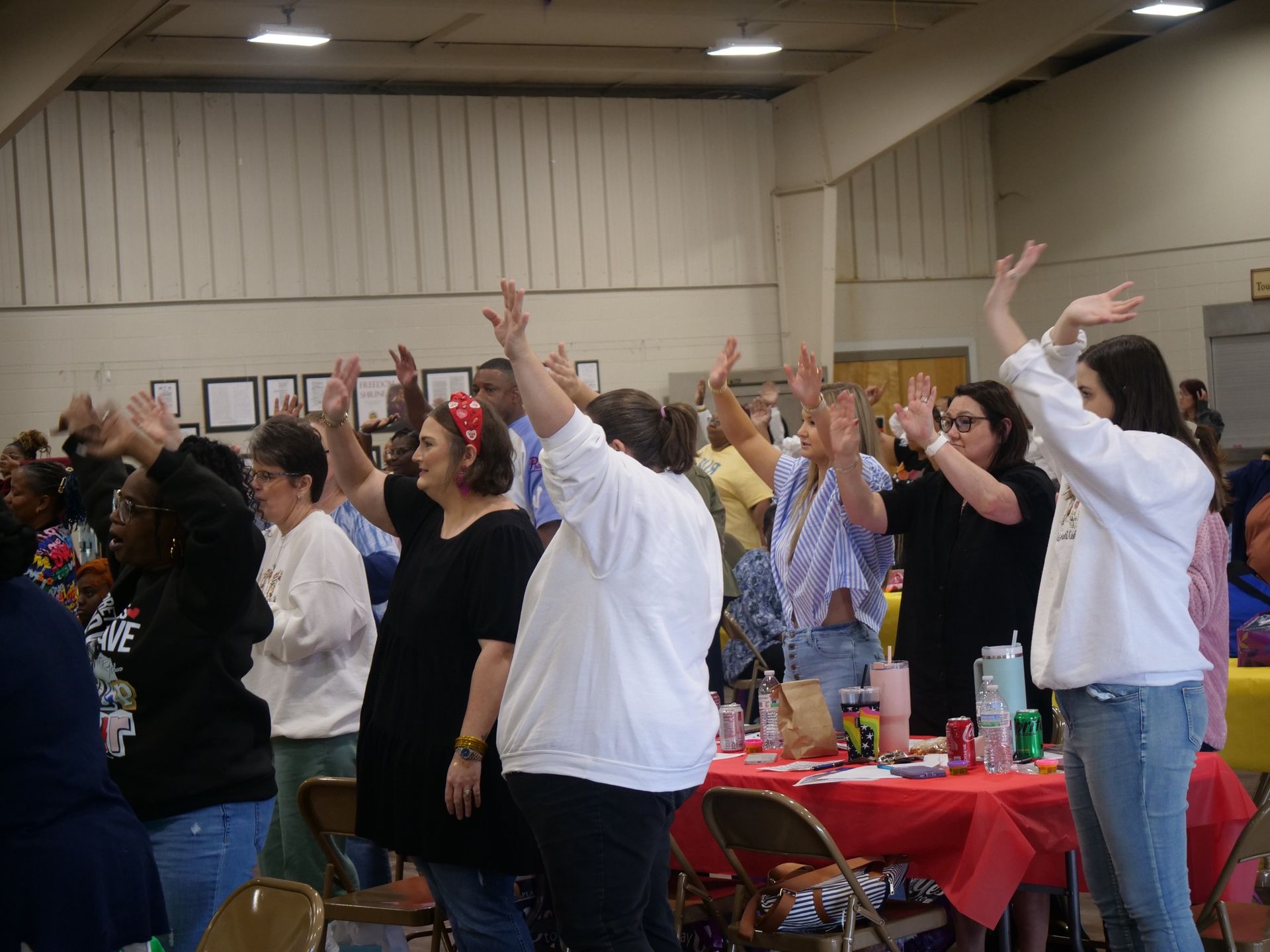 A group of people are standing in a room with their hands in the air.