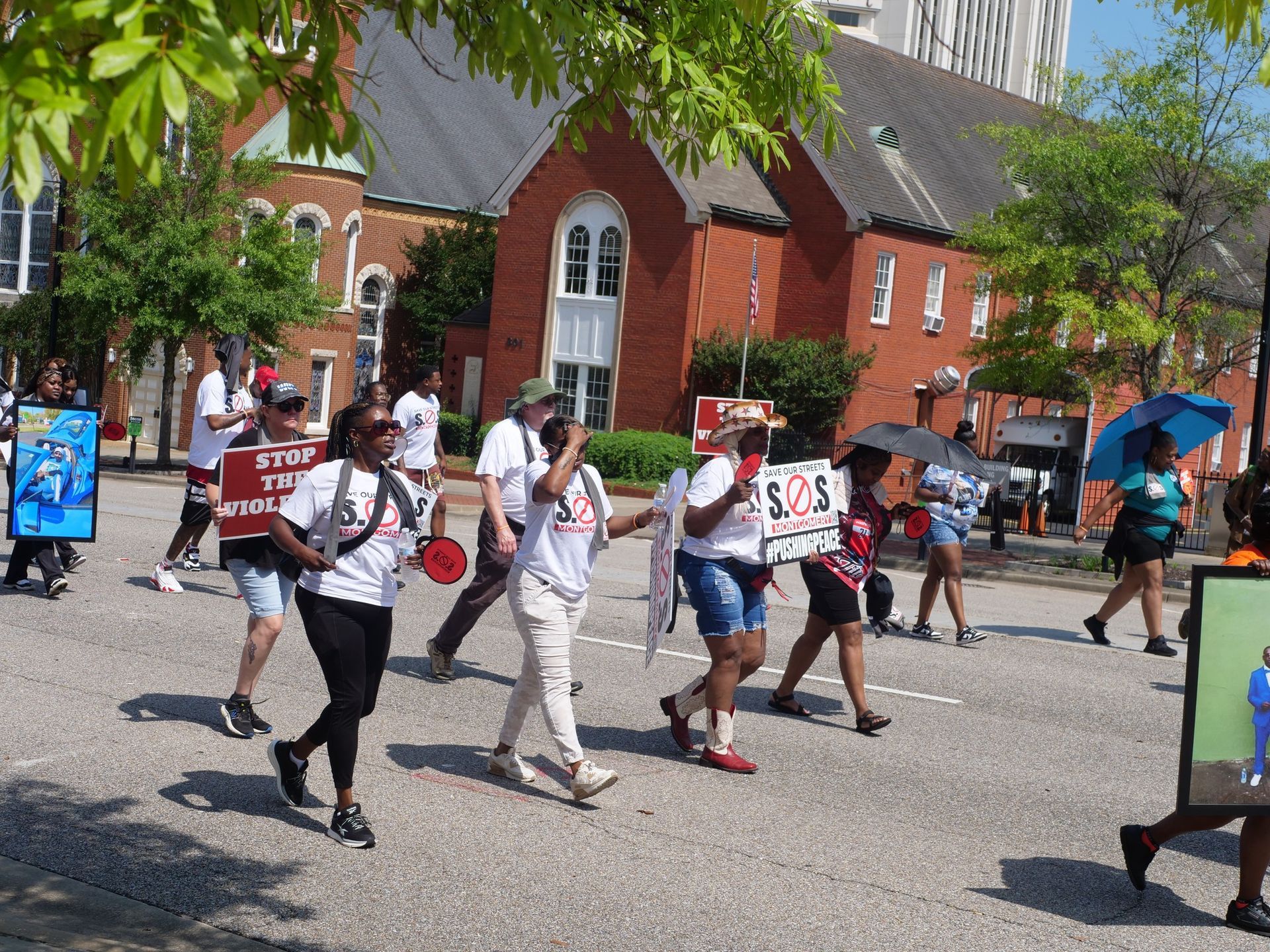 A group of people are walking down a street holding signs.