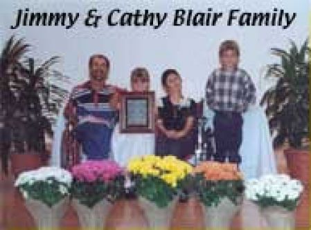 A family posing for a picture with flowers in front of them.