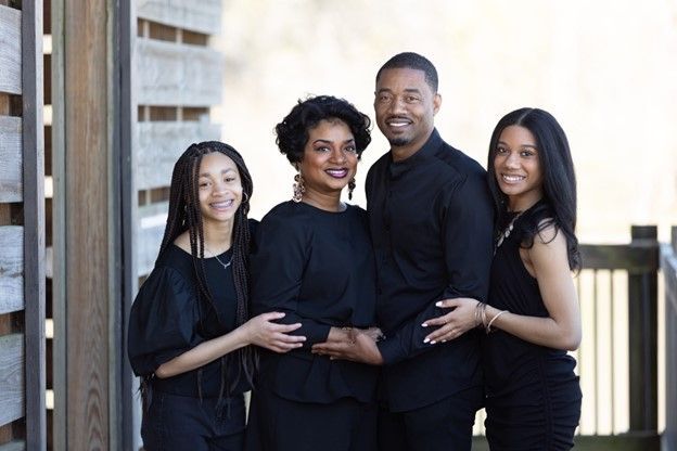 A family is posing for a picture in front of a wooden building.