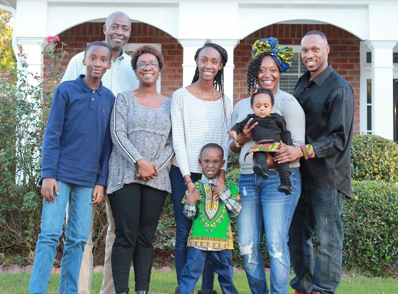 A family is posing for a picture in front of a brick house.