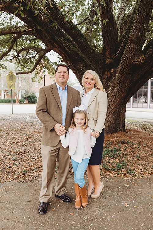 A family is posing for a picture in front of a tree.
