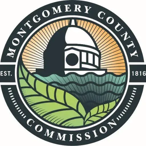 The logo for montgomery county commission is a circle with a building in the middle.