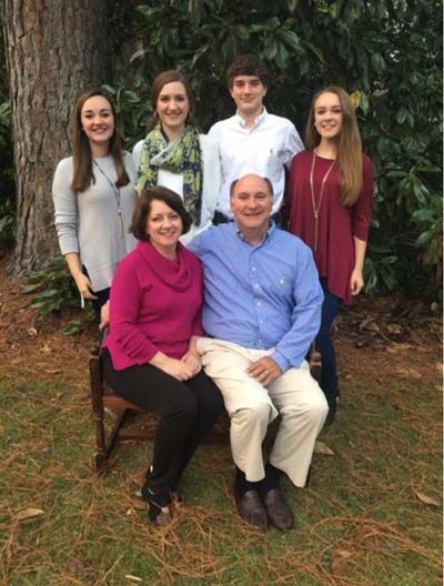 A family posing for a picture in front of a tree.