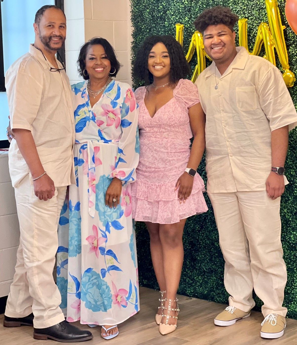 A family is posing for a picture together in front of a green wall.