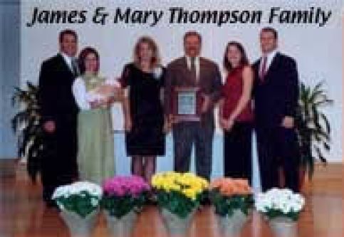A group of people standing next to each other in front of flowers.