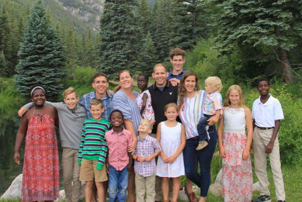 A large family is posing for a picture in front of a lake.