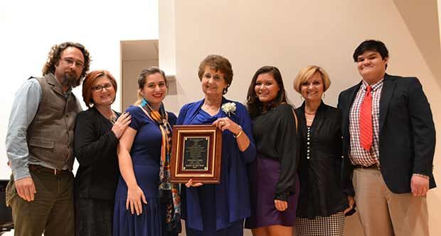A group of people standing around a woman holding a plaque.