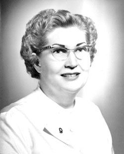 A black and white photo of a woman wearing glasses and a white shirt.