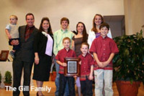 The gill family is posing for a picture with a plaque.