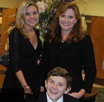 Two women and a boy are posing for a picture and the boy is smiling