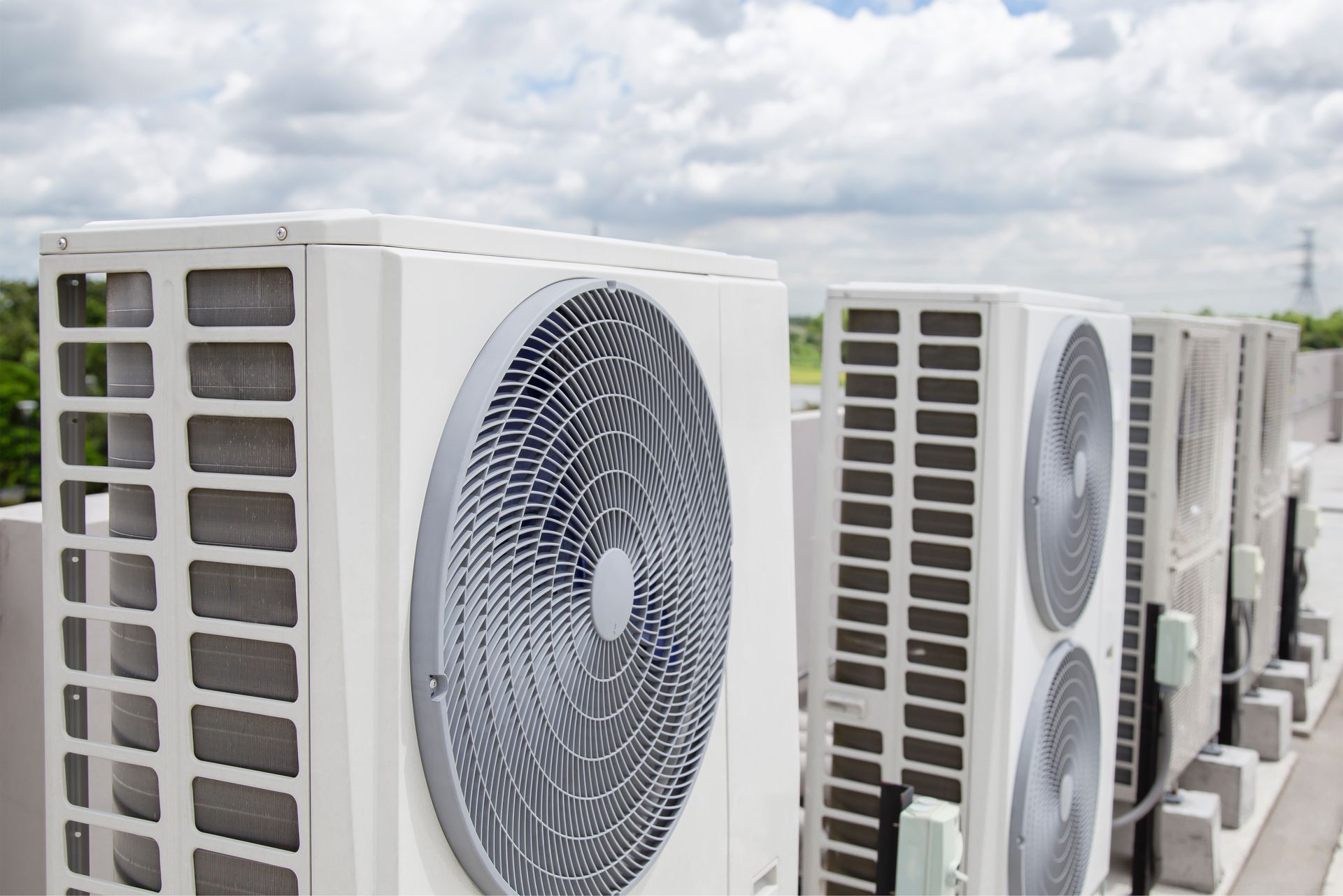 Una fila di condizionatori d'aria con pompa di calore sono posizionati in cima a un edificio.