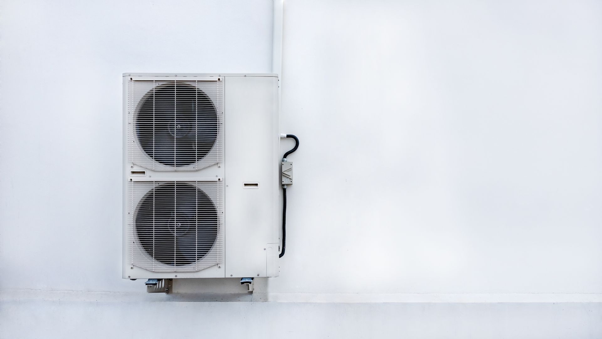 Un condizionatore bianco con pompa di calore è montato su una parete bianca.