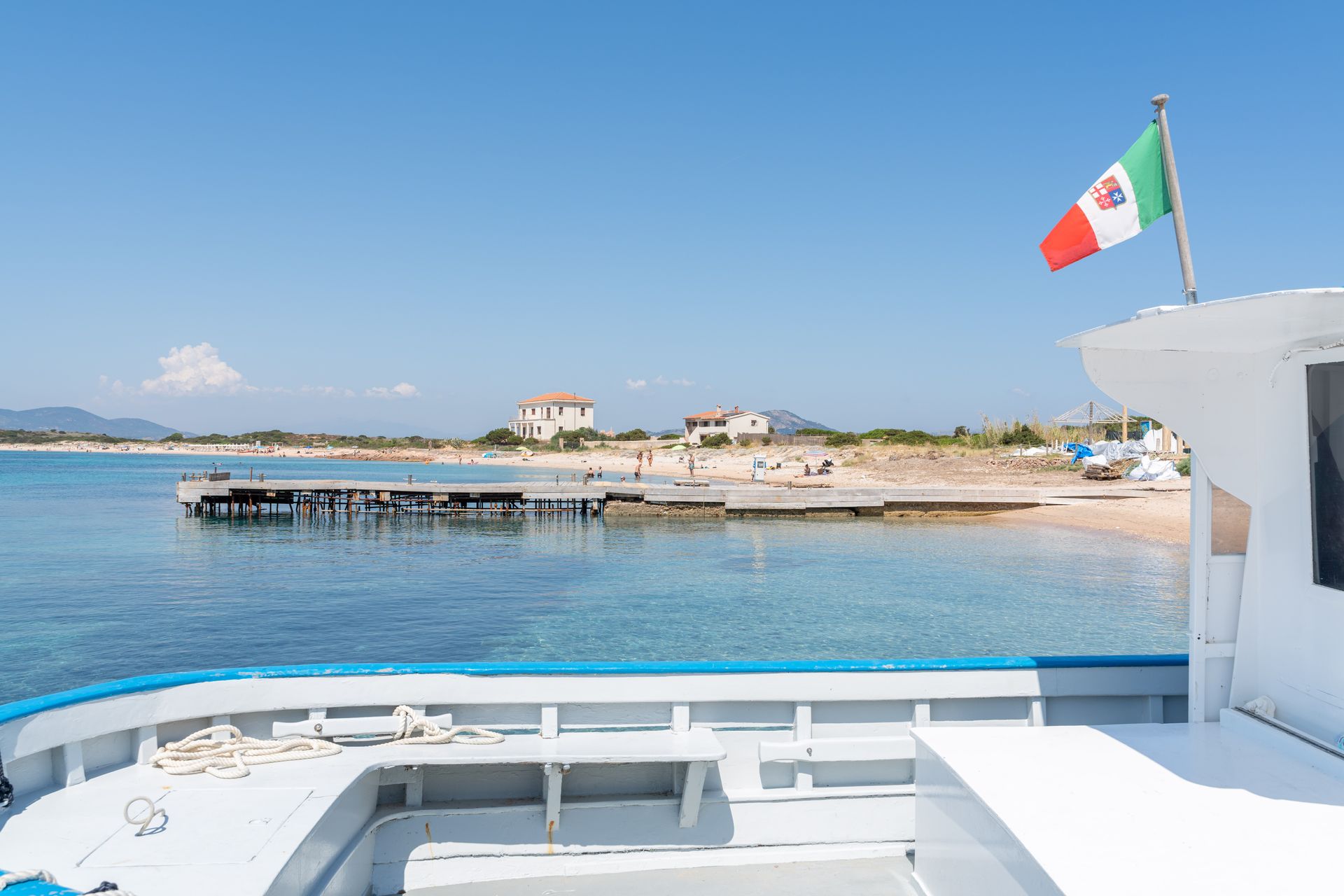 La barca naviga sul mare blu verso un'isola rocciosa sotto un cielo soleggiato.