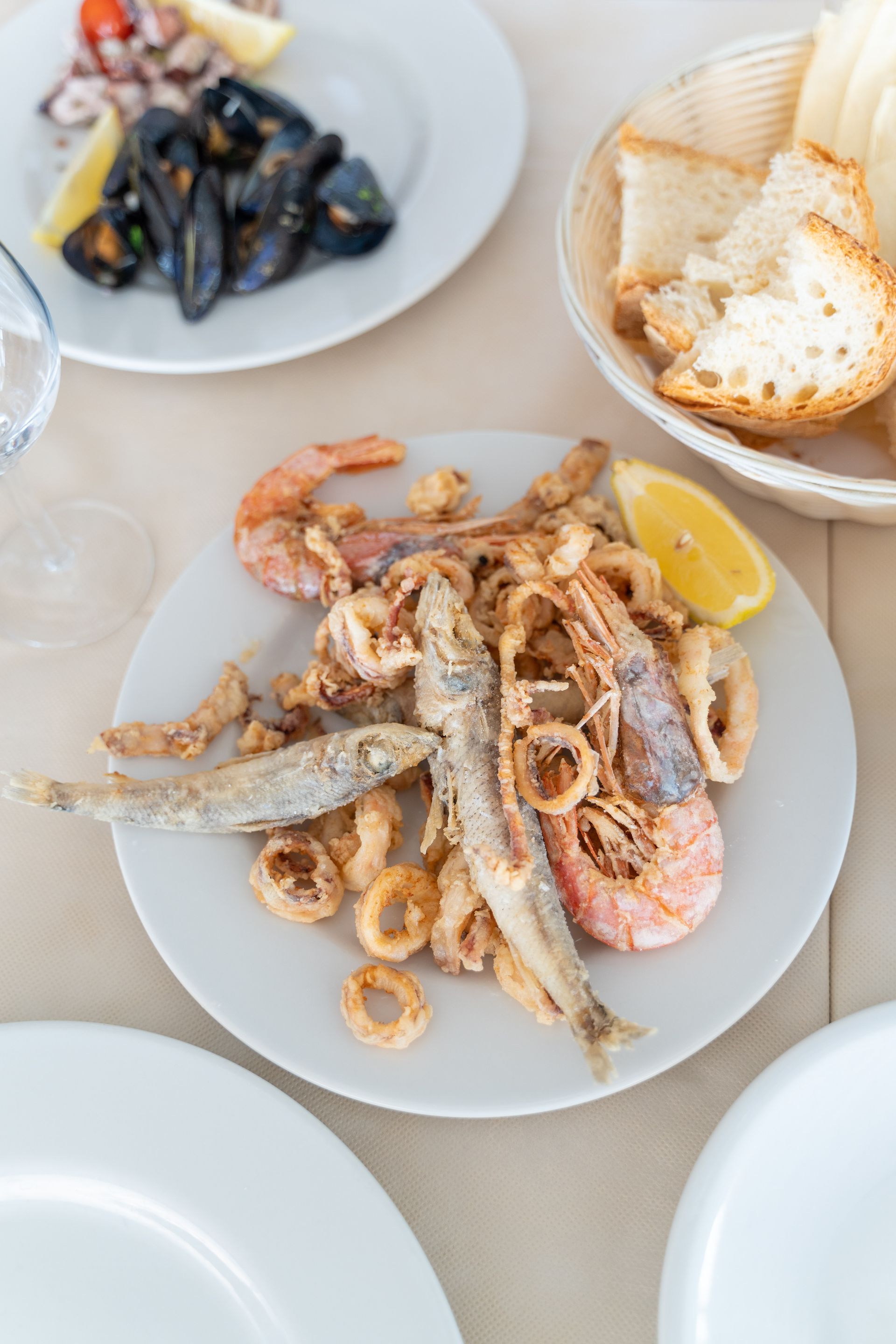 Piatto di pasta con vongole, vino bianco e pane in un ristorante sul lungomare.